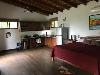 a bedroom with a red bed and a kitchen at Villas Lambeau #2 Ocean View Fiber Optic in Uvita