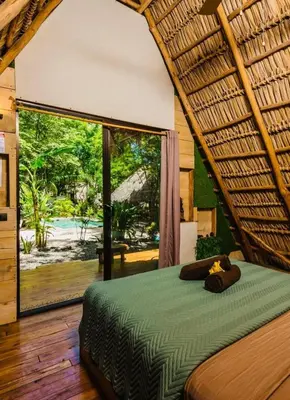 a bedroom with a bed with a large window at Cabinas de Lou Eco Lodge TAMARINDO do not book, under maintenance in Santa Rosa