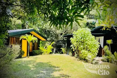 a garden with a yellow house and some trees at Casita Verde, 800 mts from beach in Playa Hermosa
