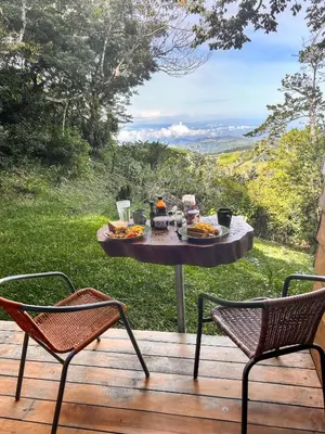a table with food sitting on a deck with two chairs at Casa Por Fin in Monteverde Costa Rica