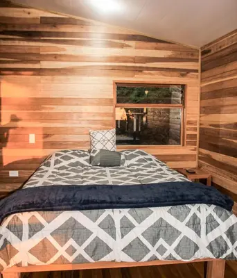 a bedroom with a bed with wooden walls and a window at Casa Por Fin in Monteverde Costa Rica