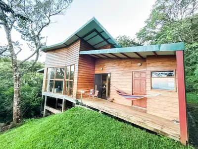 a house on a hill with a hammock on the deck at Casa Por Fin in Monteverde Costa Rica