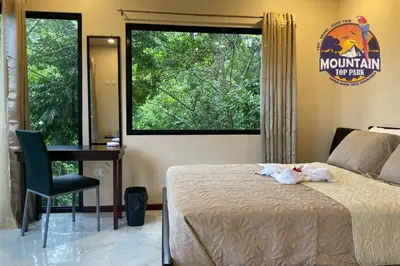 a bedroom with a bed and a desk and a window at Mountain Top Park Hotel in Manuel Antonio