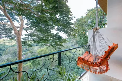 an orange hammock hanging from a balcony with trees at Mountain Top Park Hotel in Manuel Antonio