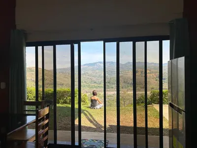 a woman sitting on a hill looking out of a window at Conectar con la naturaleza in Esparza