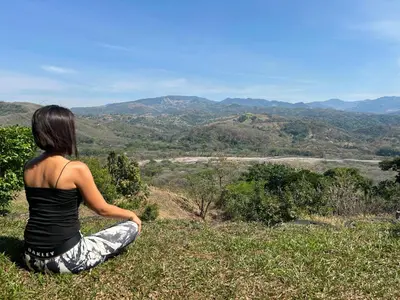 a woman sitting on a hill looking at the mountains at Conectar con la naturaleza in Esparza