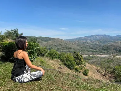 a woman sitting on a hill looking at the mountains at Conectar con la naturaleza in Esparza