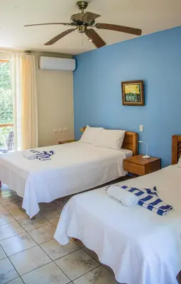 two beds in a room with a blue wall at Hotel Sol Sámara in Sámara