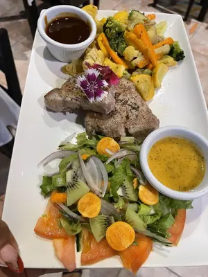 a plate of food with meat and vegetables and dipping sauce at Hotel Sol Sámara in Sámara