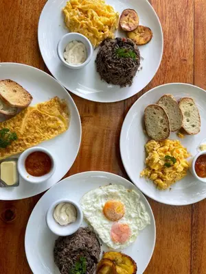 four plates of breakfast foods on a wooden table at Hotel Sol Sámara in Sámara