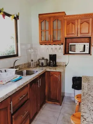 a kitchen with wooden cabinets and a sink at Holiday Beach House In Punta Leona - wprivate Pool in Punta Leona
