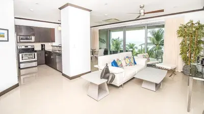 a living room with a white couch and a kitchen at Best in Jaco Condos at Diamante del Sol in Jacó
