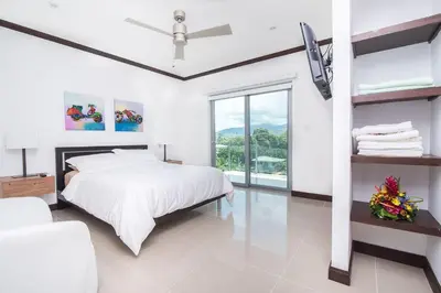 a white bedroom with a bed and a large window at Best in Jaco Condos at Diamante del Sol in Jacó