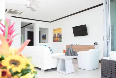 a living room with white furniture and a tv at Best in Jaco Condos at Diamante del Sol in Jacó