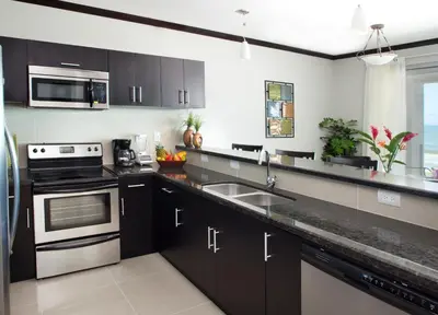 a kitchen with black cabinets and a stainless steel sink at Best in Jaco Condos at Diamante del Sol in Jacó