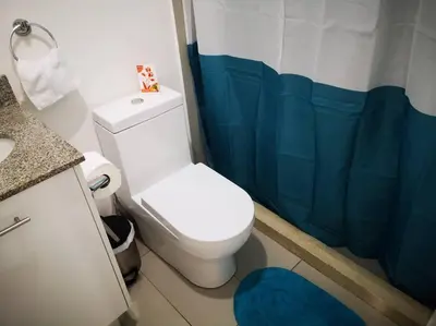 a bathroom with a white toilet and a blue shower curtain at 0201 iFreses Hermoso Apartamento Full Equipado SIN PARQUEO in Curridabat