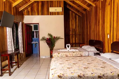 a bedroom with two beds and a tv in it at Selvita Lodge Arenal in Fortuna