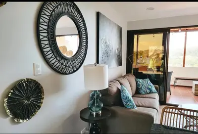 a living room with a couch and a mirror at Cozy Resort Beach Condo in Playa Hermosa in Sardinal