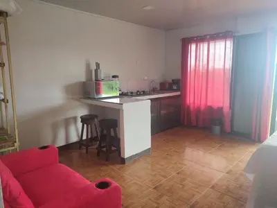 a living room with a red couch and a kitchen at Cabinas equipadas Cóbano - Florida in Tambor