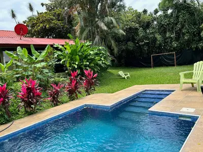 a swimming pool in a yard with a chair and flowers at B&B Garden Grecia in Grecia
