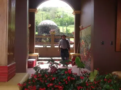 a man standing in the hallway of a building with flowers at Lake Arenal Killer View Villa in Tilarán