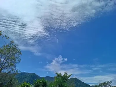 a blue sky with clouds and trees and mountains at Cabaña Paraíso Verde in Providencia