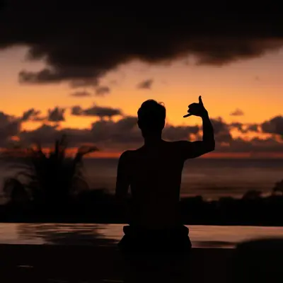 a man sitting on the beach with a bird in his hand at Grand Oceanview Villas - Casa Aria and Casa Magnifique in Santa Teresa Beach