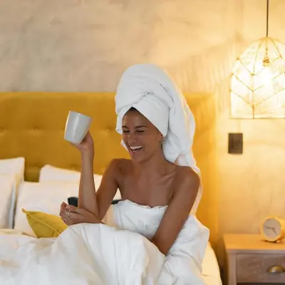 a woman sitting in bed holding a cup of coffee at Grand Oceanview Villas - Casa Aria and Casa Magnifique in Santa Teresa Beach