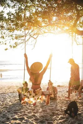 a woman sitting on a swing on the beach at Grand Oceanview Villas - Casa Aria and Casa Magnifique in Santa Teresa Beach