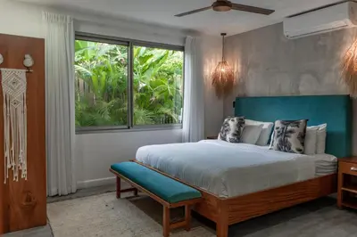 a bedroom with a bed with a blue headboard and a window at Grand Oceanview Villas - Casa Aria and Casa Magnifique in Santa Teresa Beach