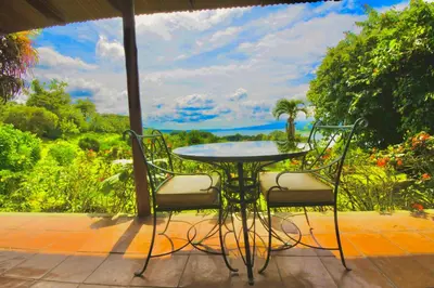 a table and chairs on a patio with a view of the ocean at Hotel La Mansion Inn Arenal in Nuevo Arenal