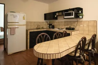 a kitchen with a table and a white refrigerator at Anona Guesthouse in Playa Hermosa
