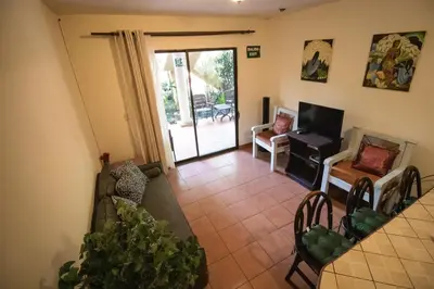 a living room with a table and chairs and a television at Anona Guesthouse in Playa Hermosa