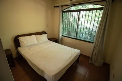 a small bedroom with a bed and a window at Anona Guesthouse in Playa Hermosa