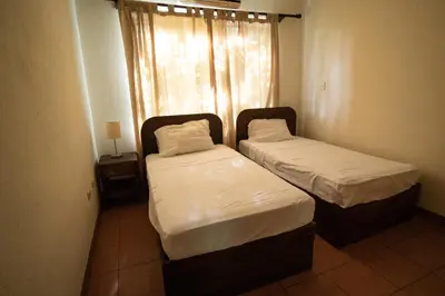 two beds in a small room with a window at Anona Guesthouse in Playa Hermosa