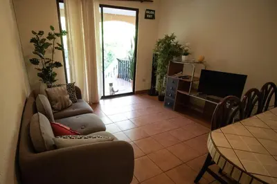 a living room with a couch and a table and a television at Anona Guesthouse in Playa Hermosa