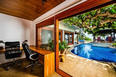 an office with a desk and a swimming pool at Casa Arrecife - 5bdr Beachfront Villa - Ethereal sunsets in Tamarindo
