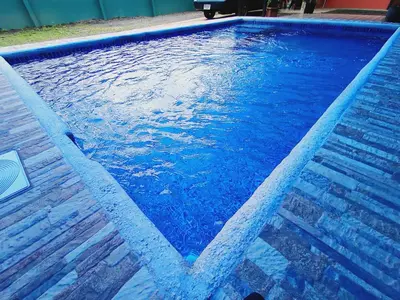 a swimming pool with blue water and a wooden floor at Arenal Palacios in Fortuna