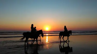 two people riding horses on the beach at sunset at AYLA C - new, cozy Ocean view Studio in Flamingo in Playa Flamingo