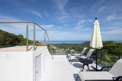 a patio with chairs and an umbrella and the ocean at AYLA D - lovely Ocean view Studio in Flamingo in Playa Flamingo