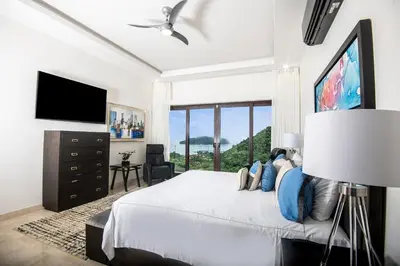 a bedroom with a large bed and a flat screen tv at Casa Mar CR in Herradura
