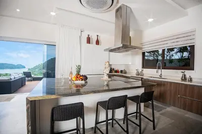 a kitchen with a counter with chairs and a large window at Casa Mar CR in Herradura