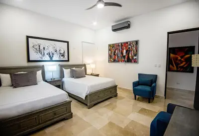a bedroom with two beds and a blue chair at Casa Mar CR in Herradura
