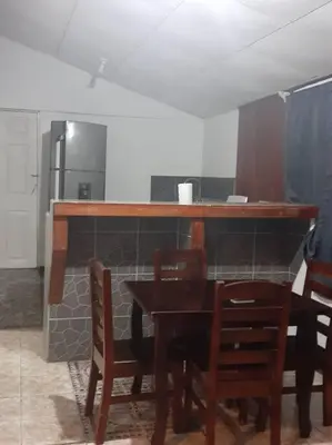 a kitchen with a wooden table with chairs and a counter at Casa Chazu in Quepos