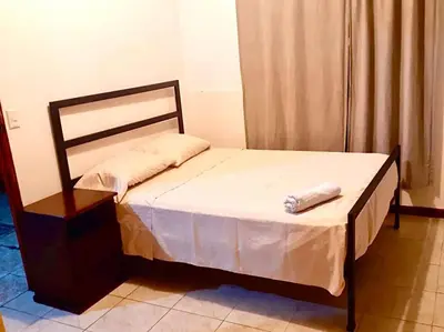 a small bedroom with a bed with a wooden frame at Casa Chazu in Quepos