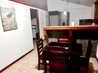 a dining room with a table and chairs and a kitchen at Casa Chazu in Quepos
