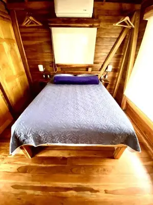 a bedroom with a bed in a wooden room at Hoja Azul - Sustainable teak modern cabin in Hojancha in Hojancha