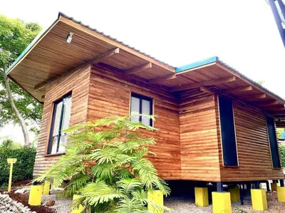 a wooden house with a tree in front of it at Hoja Azul - Sustainable teak modern cabin in Hojancha in Hojancha