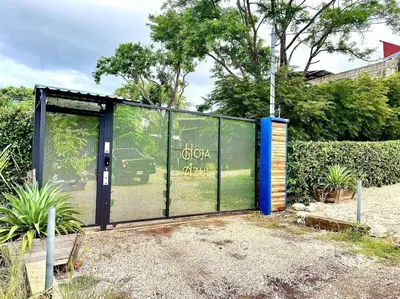 a fence with a gate with a garden behind it at Hoja Azul - Sustainable teak modern cabin in Hojancha in Hojancha