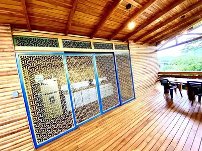 a room with wooden floors and a wall with windows at Hoja Azul - Sustainable teak modern cabin in Hojancha in Hojancha